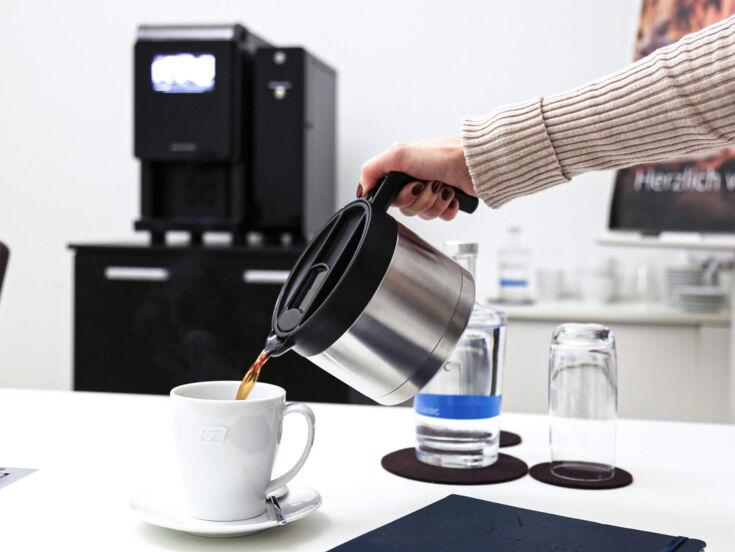 Kaffee wird aus Thermoskanne in Tasse gegossen